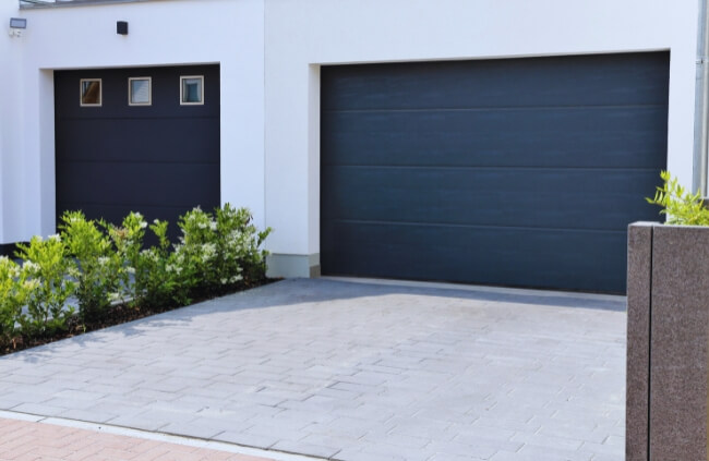 Modern home exterior featuring a stylish black garage door and paved driveway, enhancing curb appeal and contemporary home design. Modern home exterior featuring a stylish black garage door and paved driveway, enhancing curb appeal and contemporary home design.